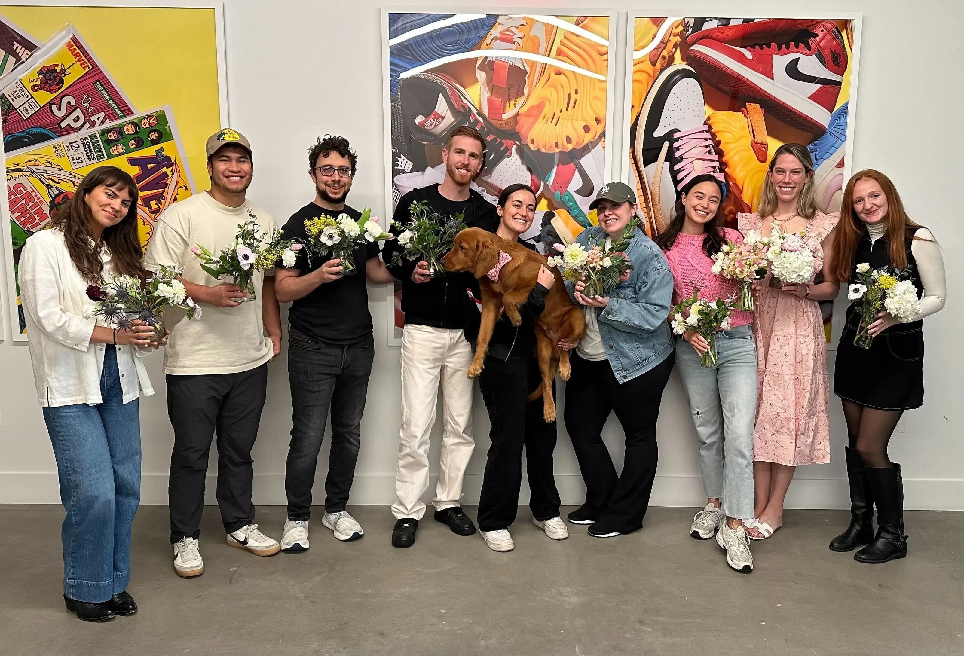 a group of women enjoying a drink and laughing in front of a colorful graphity wall